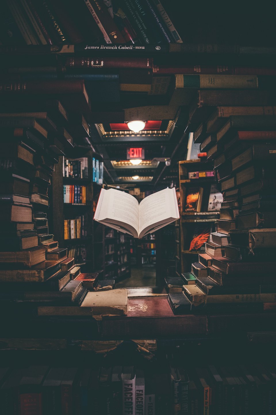 Ein aufgeschlagenes Buch schwebt in einem schwach beleuchteten Gang einer Buchhandlung.