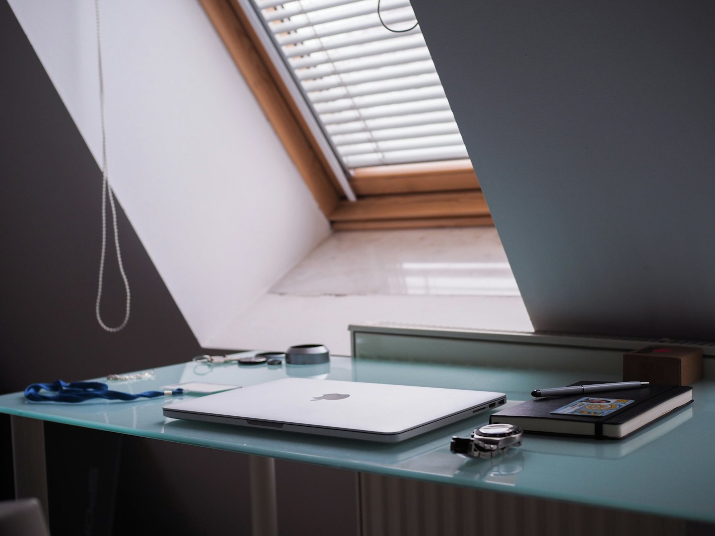 Moderner Homeoffice-Arbeitsplatz mit Laptop, Notizbuch und Stift auf einem Glastisch.